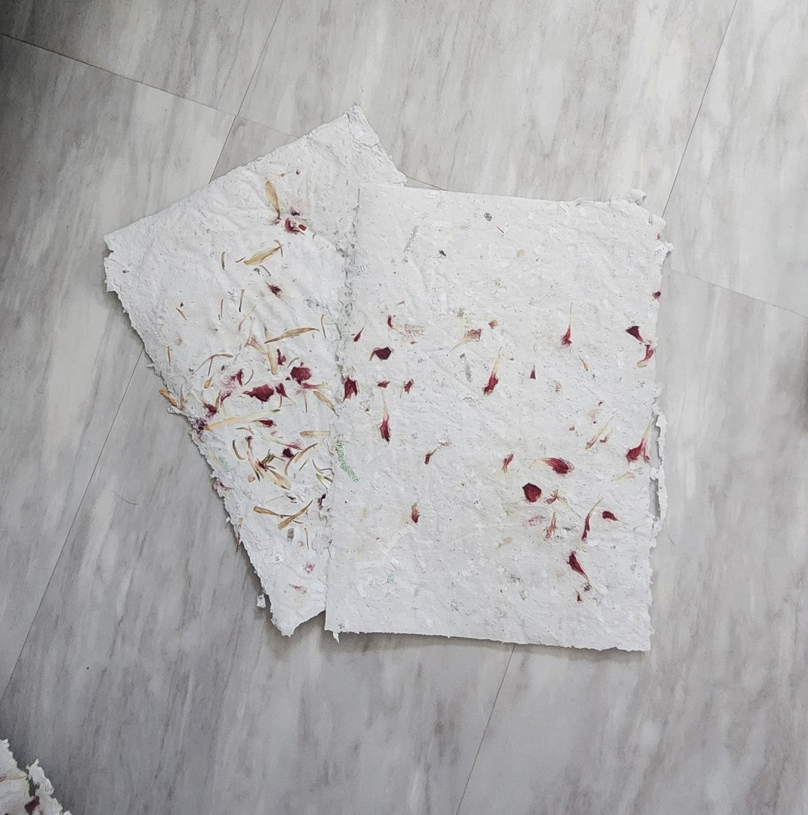 Two sheets of handmade paper with recycled paper fibers and dried flower petals