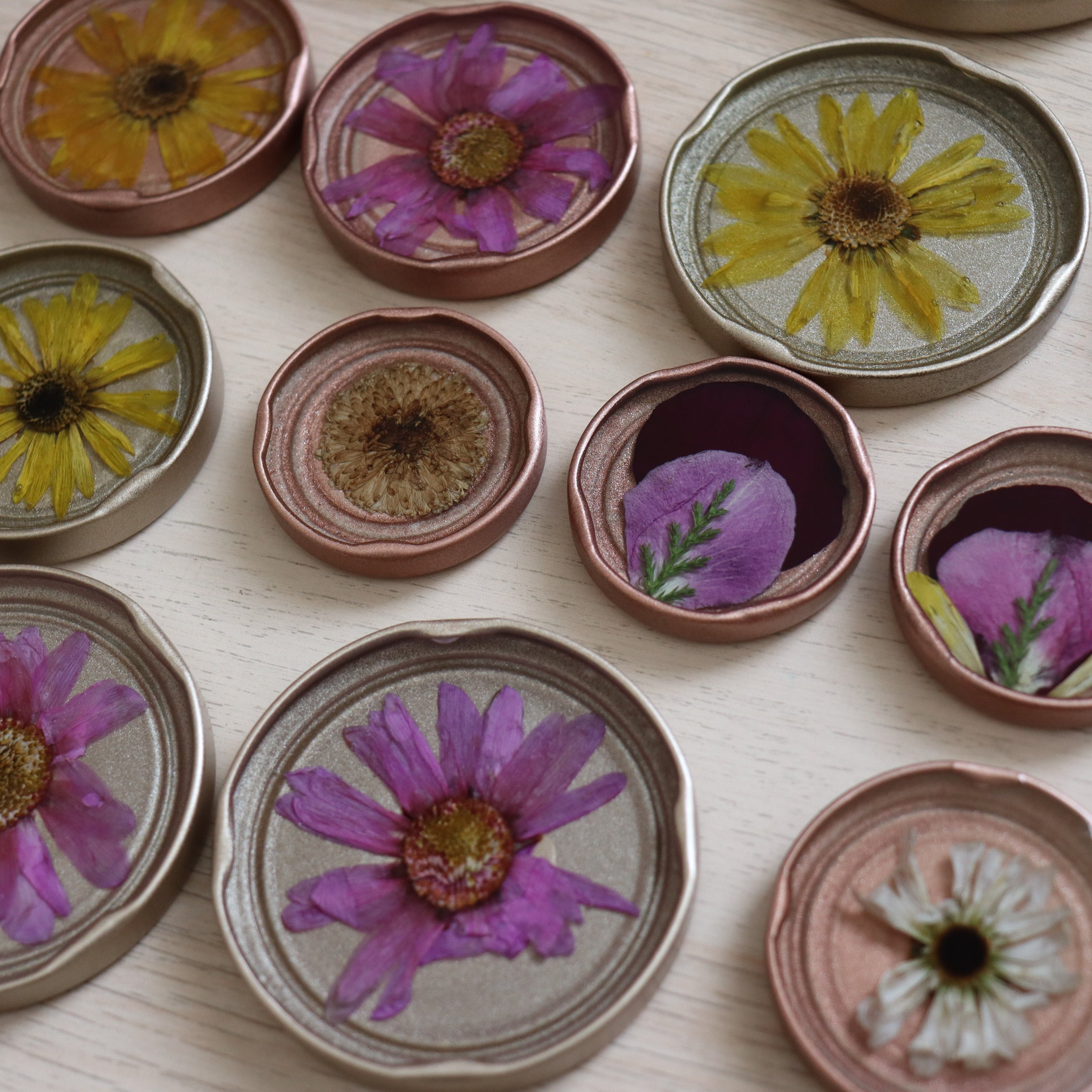Collection of pressed flower designs in metal jar lids sealed in resin